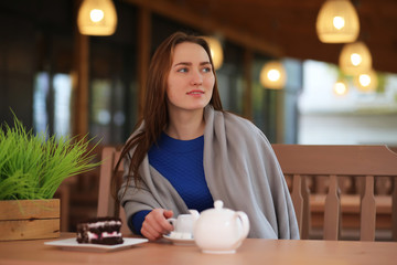 Young girl in cafe sits and drinks tea