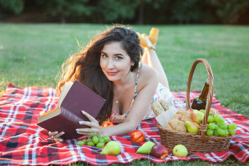 Sexy brunette woman on picnic blanket in the park.