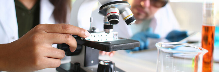 Obraz na płótnie Canvas Two scientists of a student chemist are conducting research using microscope for bacterial contamination of water to search for vaccine to treat diseases in medicine