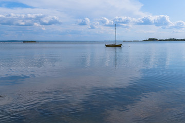 Seascape. An empty boat with a mast is anchored in the sea bay on a summer day.