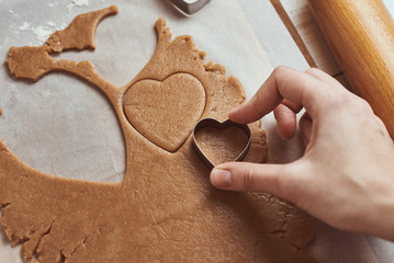 Making gingerbread cookies in the shape of a heart for Valentines Day. Woman hand use cookie...