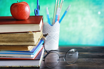 Education concept. A stack of textbooks and a book on the desk with glasses and a computer. School breakfast apple and homework.