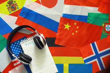 Learning foreign languages. Audio language courses. Background from countries flags and headphones on the table.