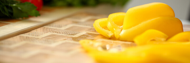 Cook holds knife in hand and cuts on cutting board yellow pepper for salad or fresh vegetable soup with vitamins. Raw food and vegetarian recipe book in modern society popular concept.