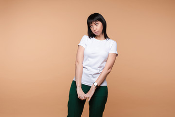 Waist up of distressed brunette in a white t-shirt standing and holding hands together. Isolated on...