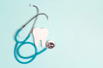 Tooth with a stethoscope on a blue background. Space for text.