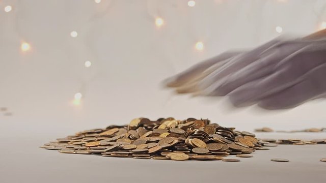 White-gloved hands scooping up a pile of gold coins. They sort out and scatter money.On white background. Garland. Money glitters.