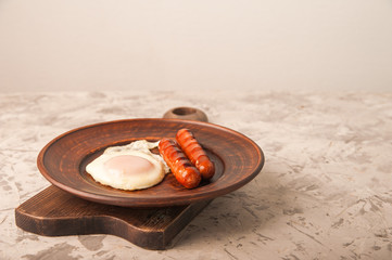 Close-up of sausages and fried eggs. Sausages on a plate and place for text. Breakfast fried eggs and bavarian sausages on a clay plate and copy space.