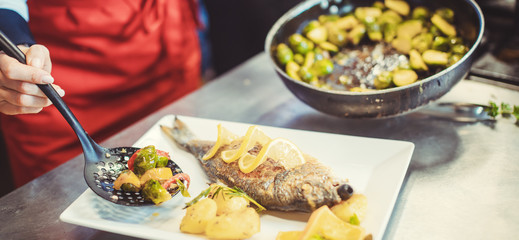 Head chef in restaurant putting food on a dish soon to be served