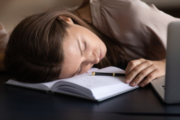 Exhausted female fall asleep working on laptop at workplace