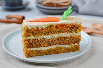Carrot Cake Day.  Carrot cake with cream cheese frosting decorated with chocolate carrots on a light wooden background. Close-up, top view
