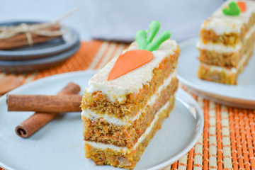 Carrot Cake Day.  National holiday. Carrot cake with cream cheese frosting decorated with chocolate carrots on an orange background, stylized table setting.  Close-up, top view .