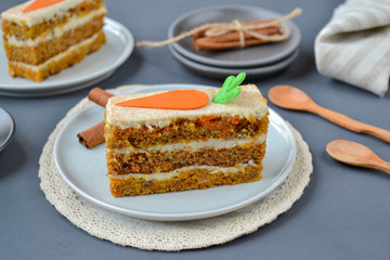 National Carrot Cake Day.  Carrot cake with cream cheese frosting decorated with chocolate carrots on a gray wooden background. Close-up, top view
