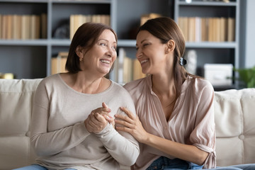 Smiling adult mom and daughter have fun chatting at home