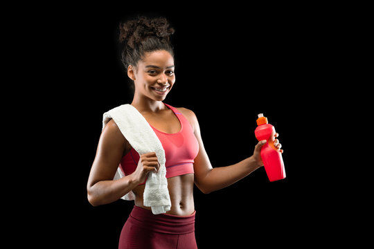 Pretty smiling sporty girl drinking water during exercising