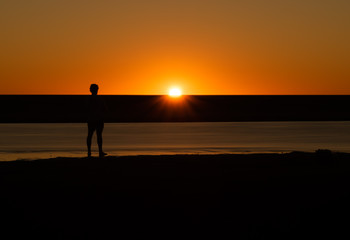 Silhouette of man watching the sunset on a riverbed in Australia