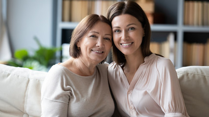 Fototapeta na wymiar Headshot portrait of senior mother and adult daughter on couch