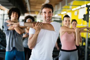 Fototapeta na wymiar Group of happy multiracial friends exercising together in gym