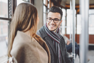 Happy couple having conversation while going to work in bus - Young people traveling in vintage...