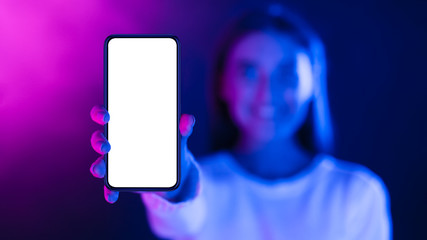 Woman showing phone with blank screen in neon lights