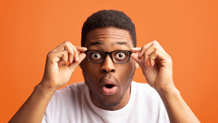 Surprised african american guy touching his eyewear