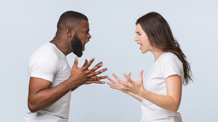 Furious multiracial couple yelling at each other, emotionally arguing and gesturing