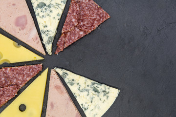 pizza topping cut as slices of pizza on black slate top view