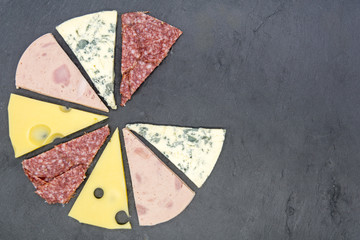 pizza topping cut as slices of pizza on black slate top view