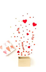 Valentine's day background.  gift box with various party confetti, red hearts and decoration isolated on white background top view. 