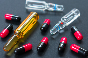 Ampoules for injection and many capsules on a black background. Close-up.