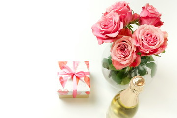 Fototapeta na wymiar Valentine's day background. Bouquet of pink roses flowers, gift box and champagne bottle isolated on white background with copy space. Top view flat lay
