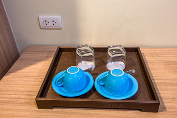 Close-up view of the blue coffee mug, clear glass for drinking water, placed on a tray to bring clear drinks, seen at resorts, hotels or bakeries