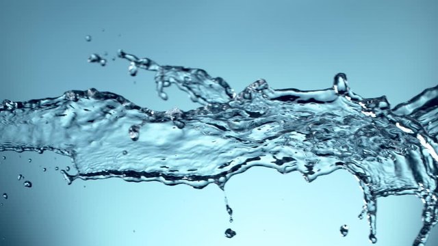 Super slow motion of flying water splashes on soft blue background. Filmed on high speed cinema camera, 1000fps.