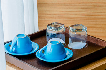 Close-up view of the blue coffee mug, clear glass for drinking water, placed on a tray to bring clear drinks, seen at resorts, hotels or bakeries