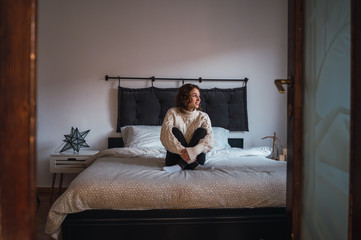 Young woman sitting in bed relaxed, smiling and enjoying the morning