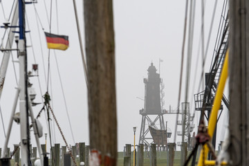 old lighthouse with low tide and fog at the northsea