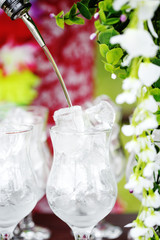 Syrup pouring in transparent glass full of ice