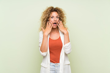 Young blonde woman with curly hair over isolated green background with surprise facial expression