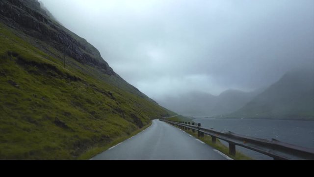 Nordic road curve landscape with forest, mountains and blue sea on background at cloudy summer day.