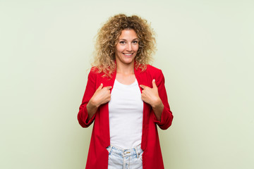 Young blonde woman with curly hair over isolated green background with surprise facial expression