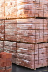 Several pallets with concrete brick stacked on top of each other in depot. Industrial production of bricks. vertical photo