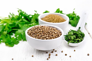 Coriander ground and seeds in bowls on light board
