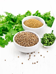 Coriander ground and seeds in bowls on white board