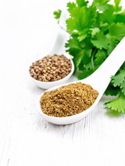 Coriander ground and seeds in spoons on white board