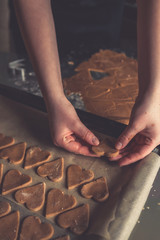 girl preparing cookies in the shape of a heart for the holiday Valentine's Day at home, in a small bakery, family business, authentic, hobby, mood, cozy. Care and love