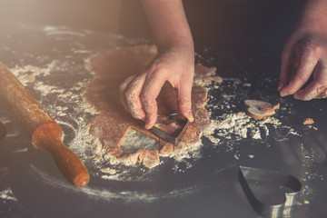 girl preparing cookies in the shape of a heart for the holiday Valentine's Day at home, in a small bakery, family business, authentic, hobby, mood, cozy. Care and love