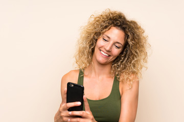 Young blonde woman with curly hair using mobile phone