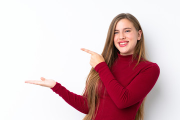 Teenager blonde girl over isolated white background holding copyspace imaginary on the palm to insert an ad