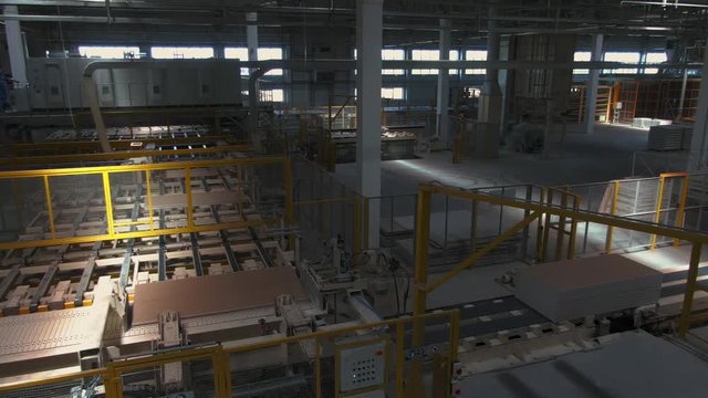 Factory production line. A worker works in a factory. Drywall production. Production of materials. Large factory machines.