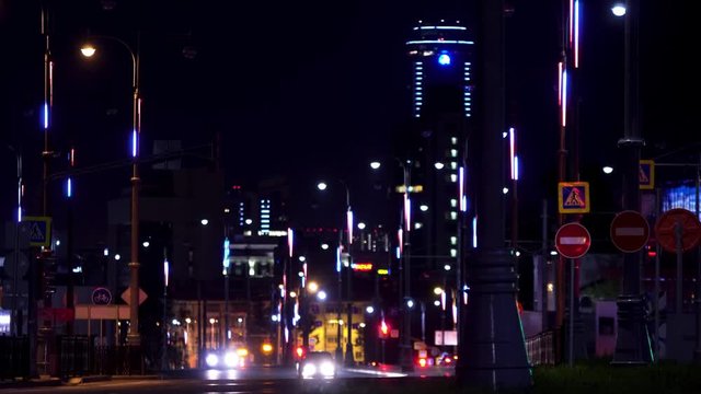 Night landscape of the big city center with shining lights and moving rare cars. Stock footage. Road of the central city district lit by street lamps.